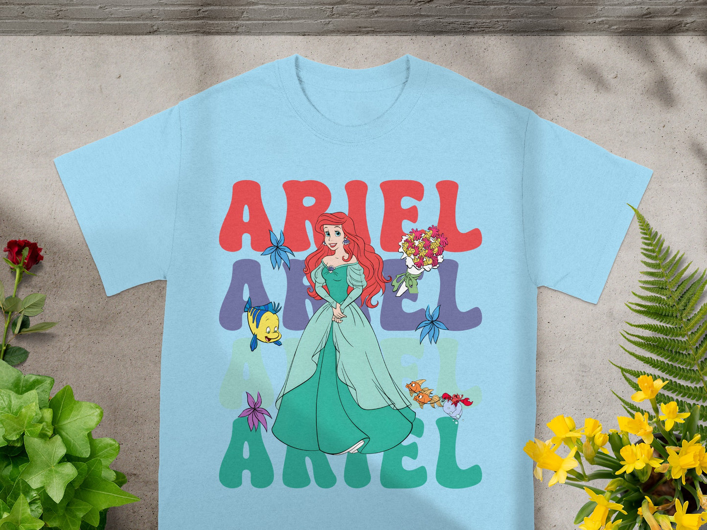 Light blue t-shirt with Ariel from The Little Mermaid graphic and text.