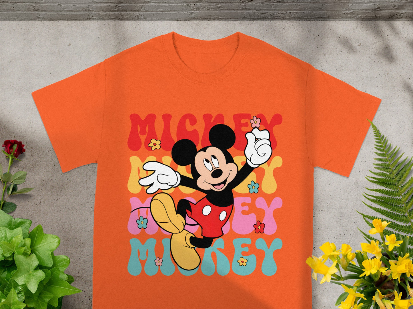Mickey Mouse graphic on an orange t-shirt with "MICKEY" text.