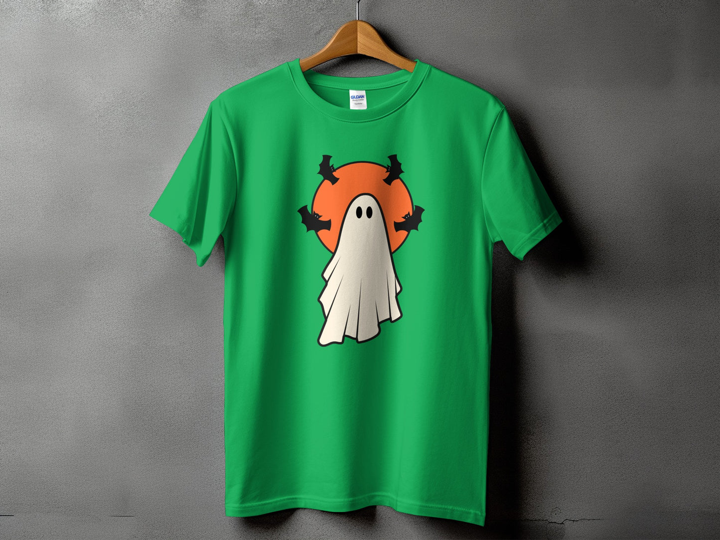 Green t-shirt with a cartoon ghost and bats against an orange circle.