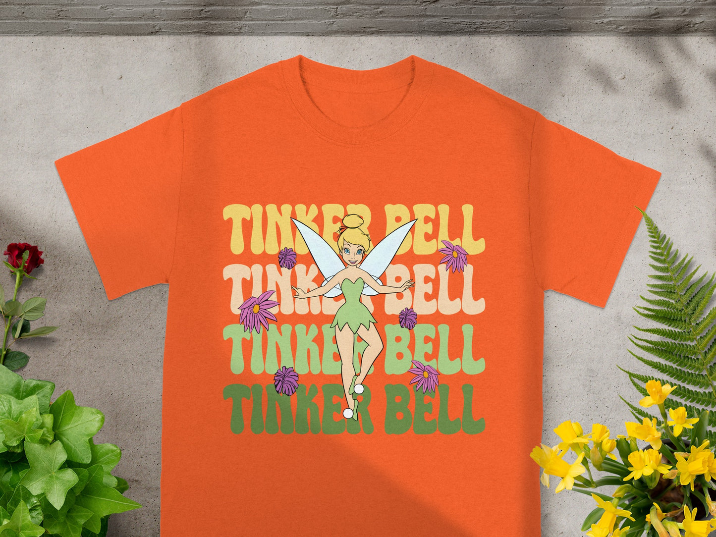 Orange t-shirt with "Tinker Bell" in colorful retro lettering.