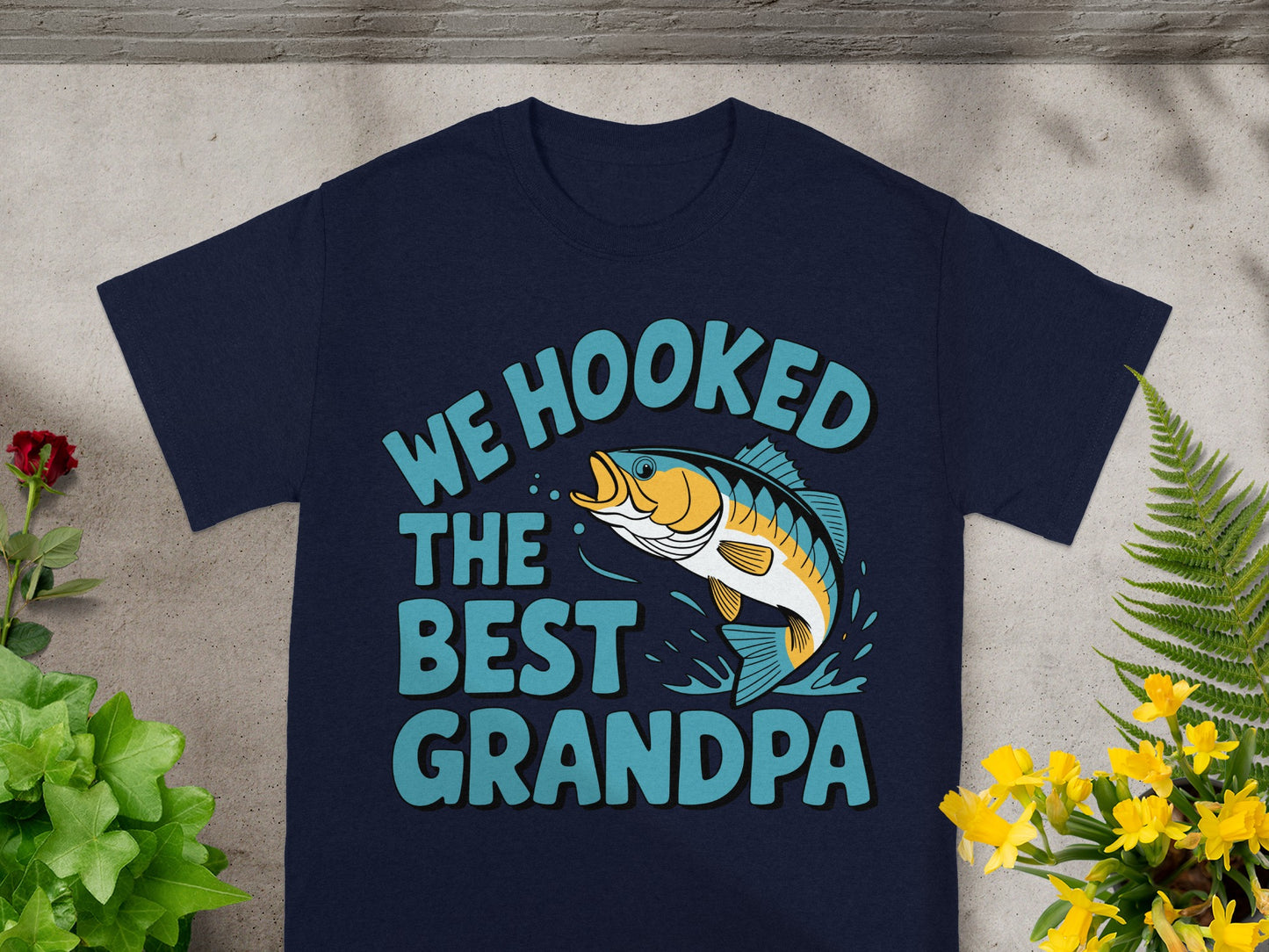 Dark blue t-shirt with text "WE HOOKED THE BEST GRANDPA" and a fish graphic.