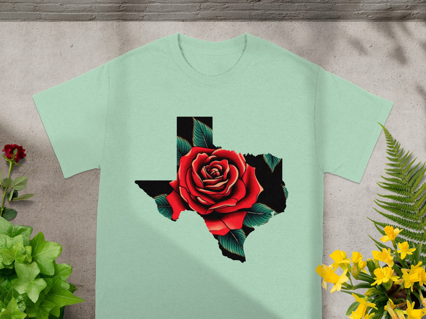 Light green t-shirt with a Texas outline filled with a red rose and green leaves.