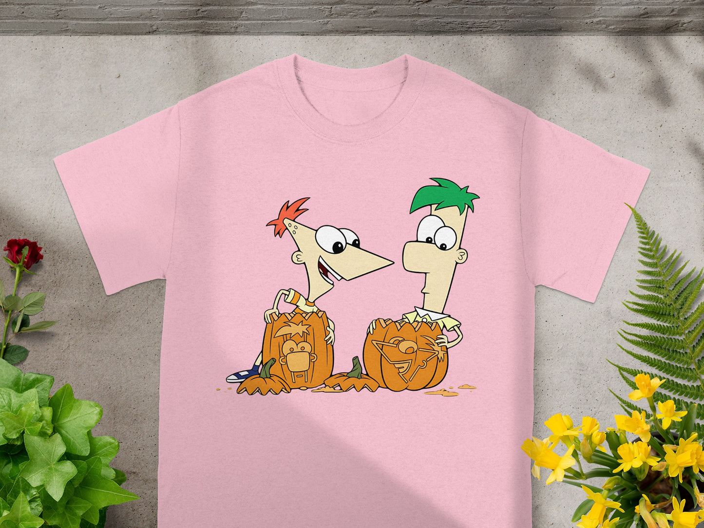Pink t-shirt with cartoon characters Phineas and Ferb carving pumpkins.