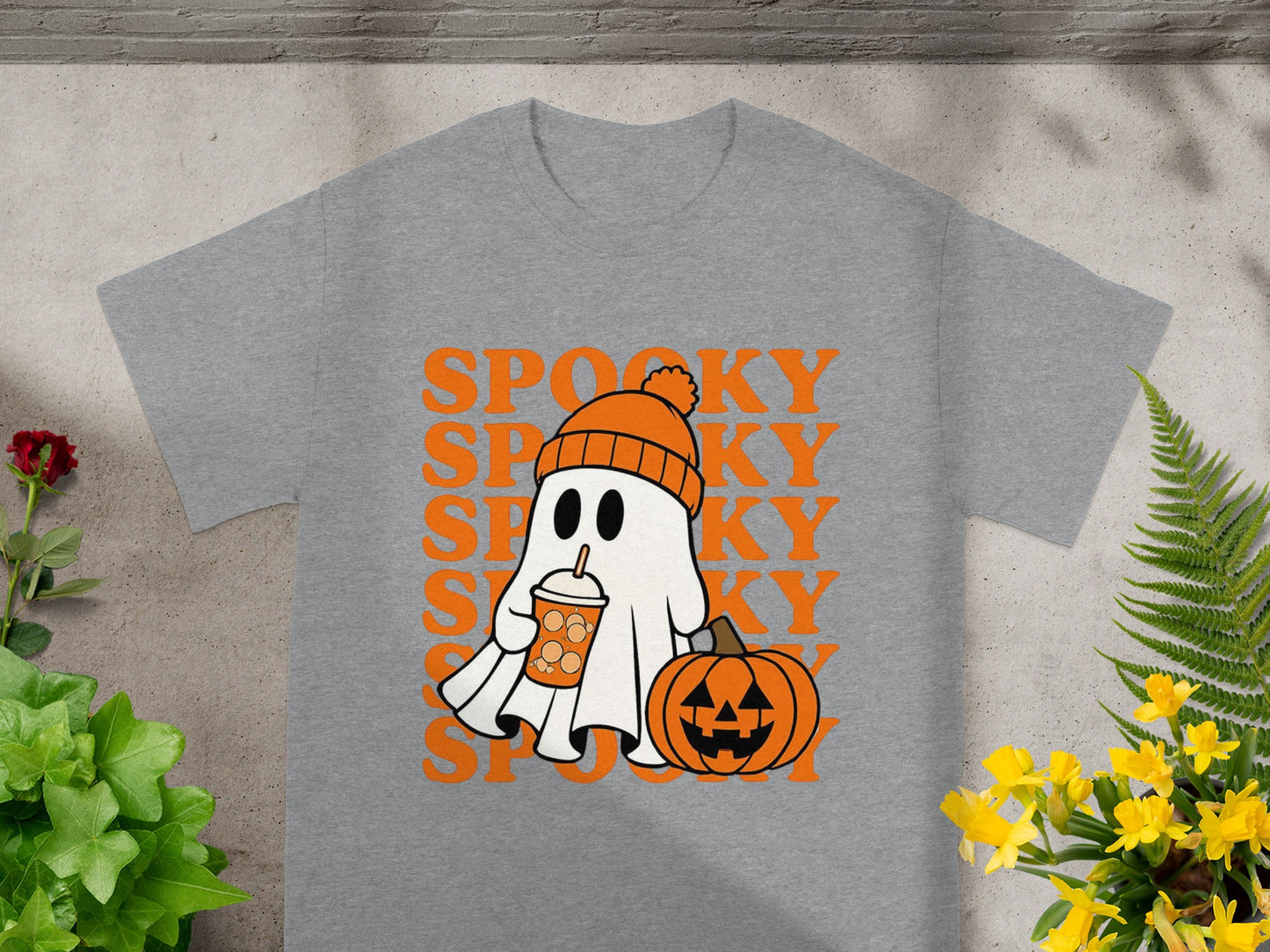 Ghost wearing beanie, holding drink, with pumpkin, on gray shirt with "SPOOKY" text.