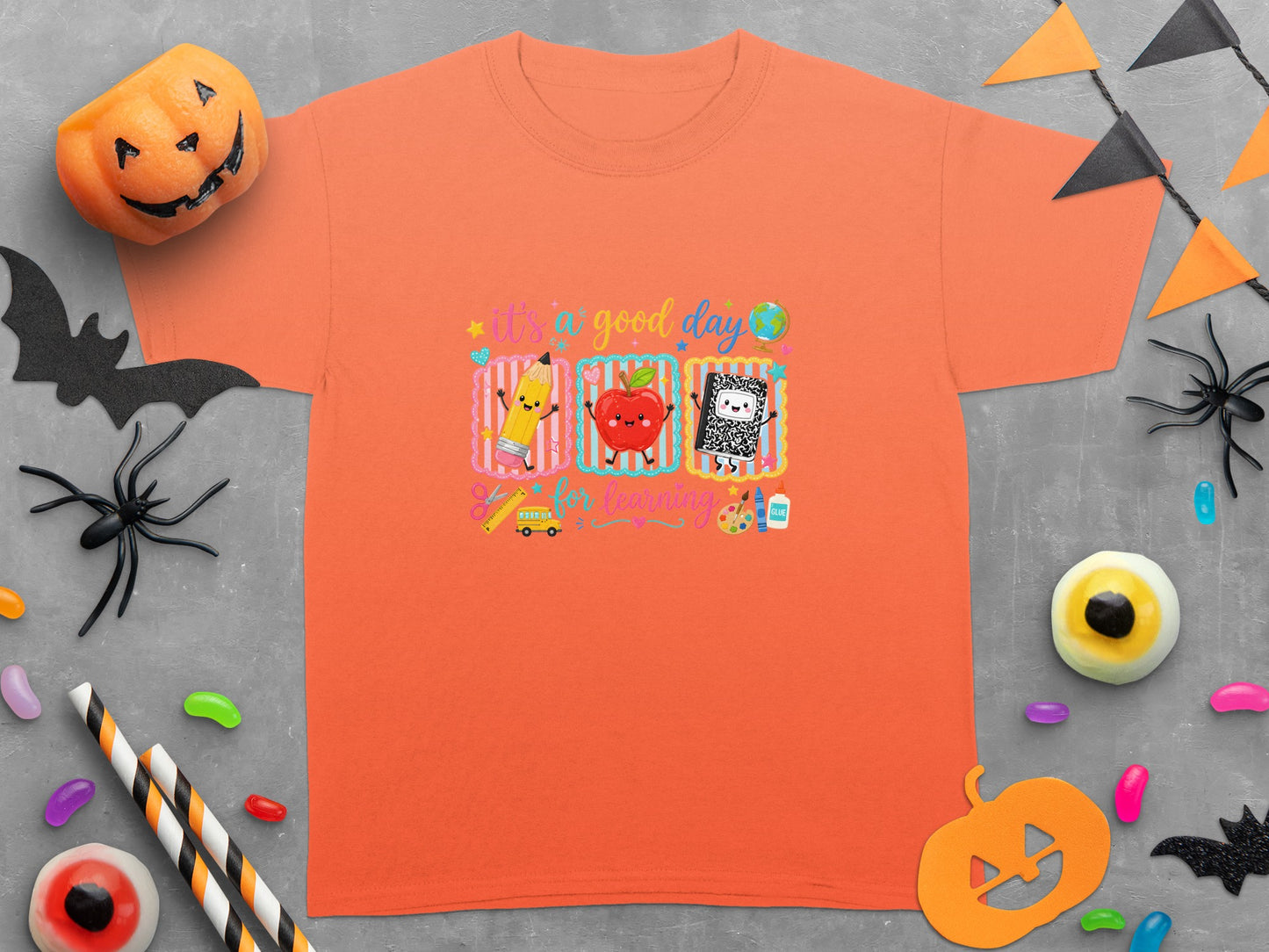 Orange t-shirt with "it's a good day for learning" and cartoon school supplies.