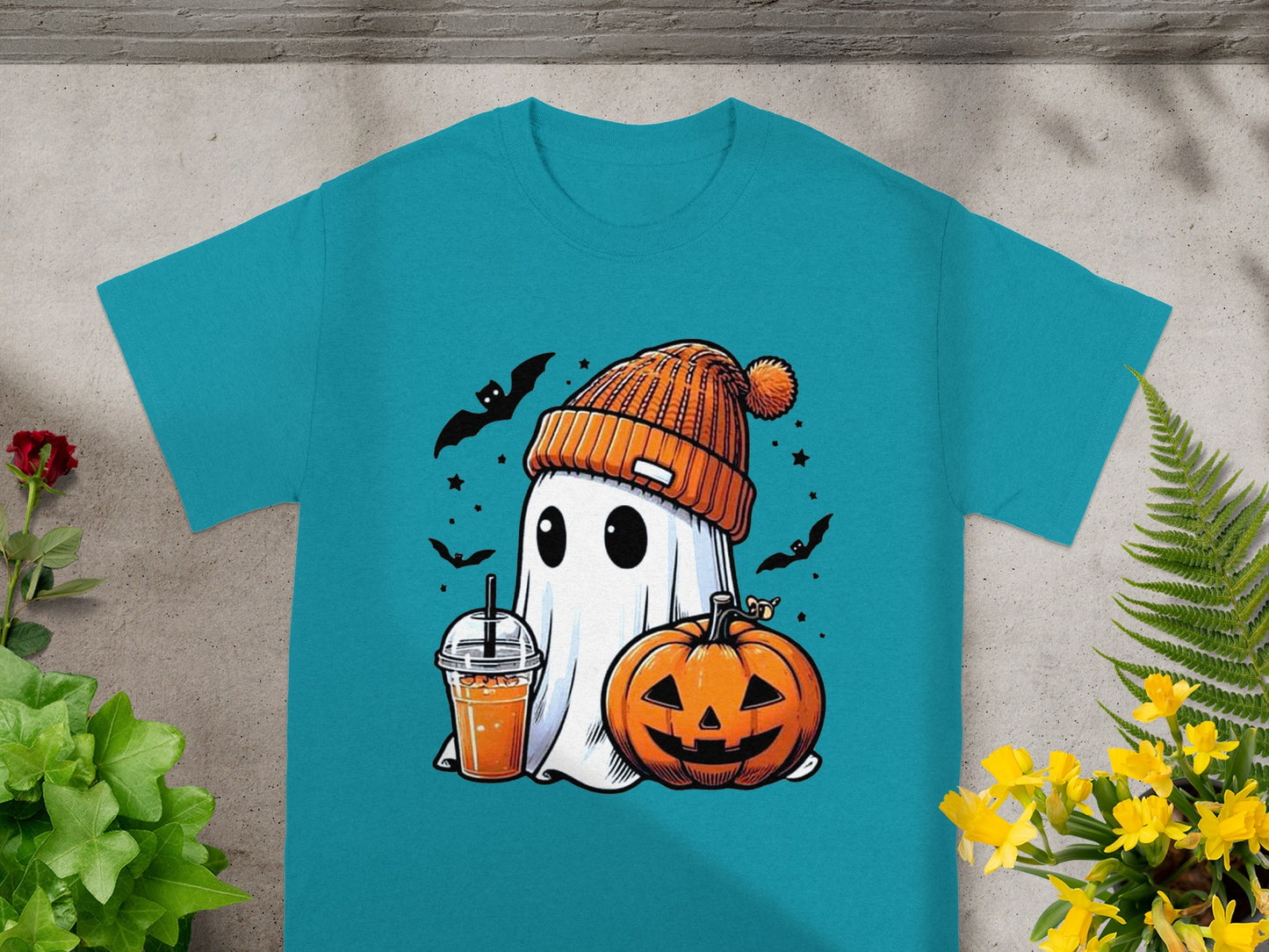 Ghost with orange hat, pumpkin, drink, and bats on a teal t-shirt.