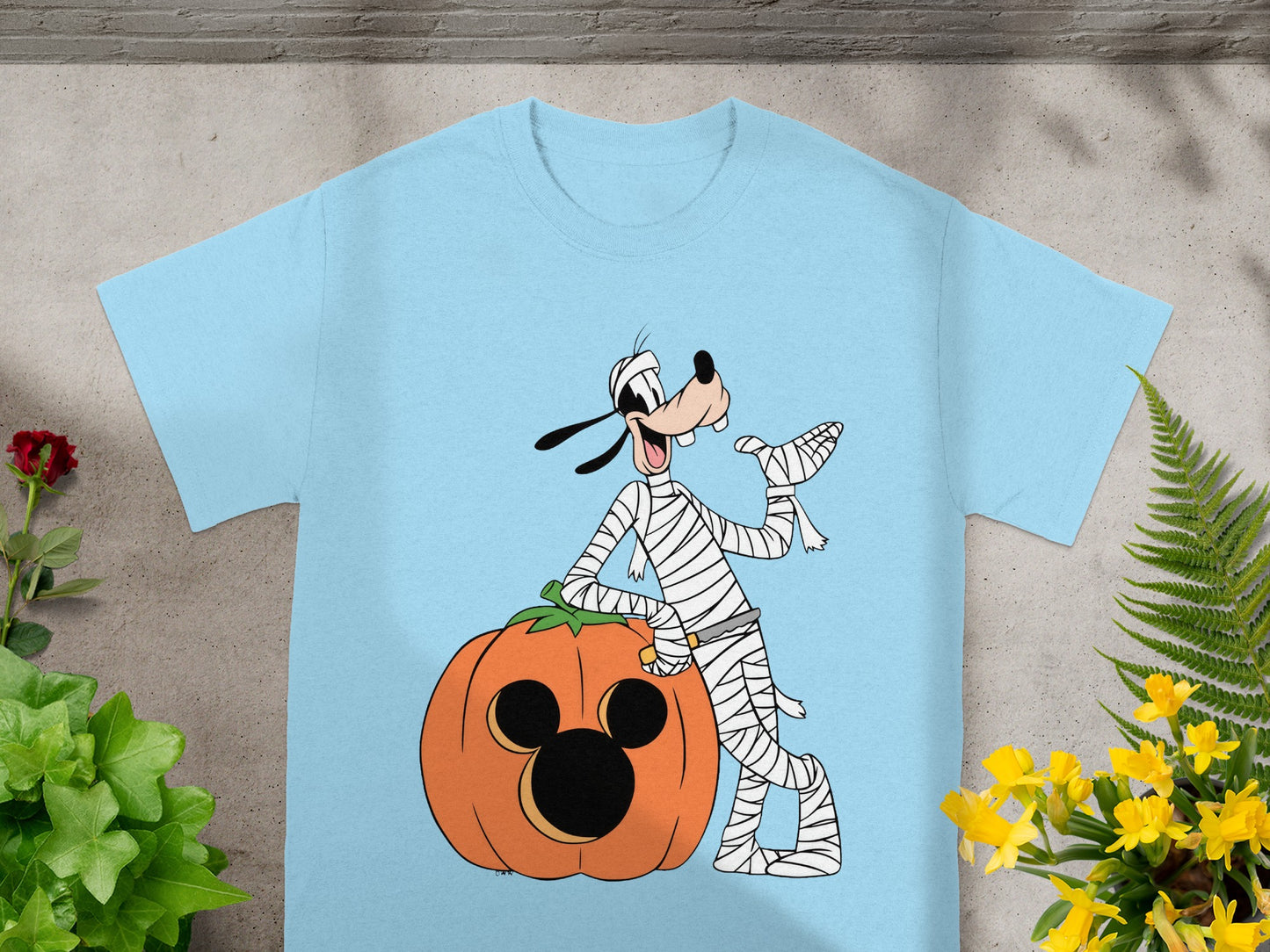 Goofy dressed as a mummy leans on a Mickey Mouse jack-o'-lantern.