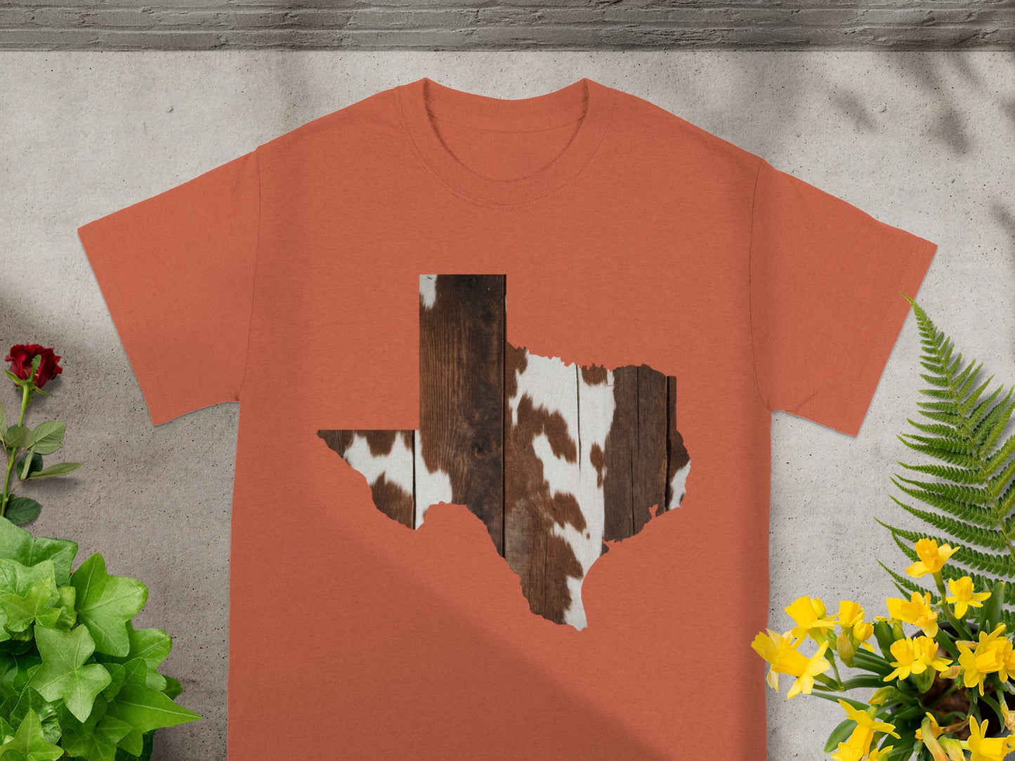 Orange t-shirt with Texas shape filled with wood and cowhide pattern.