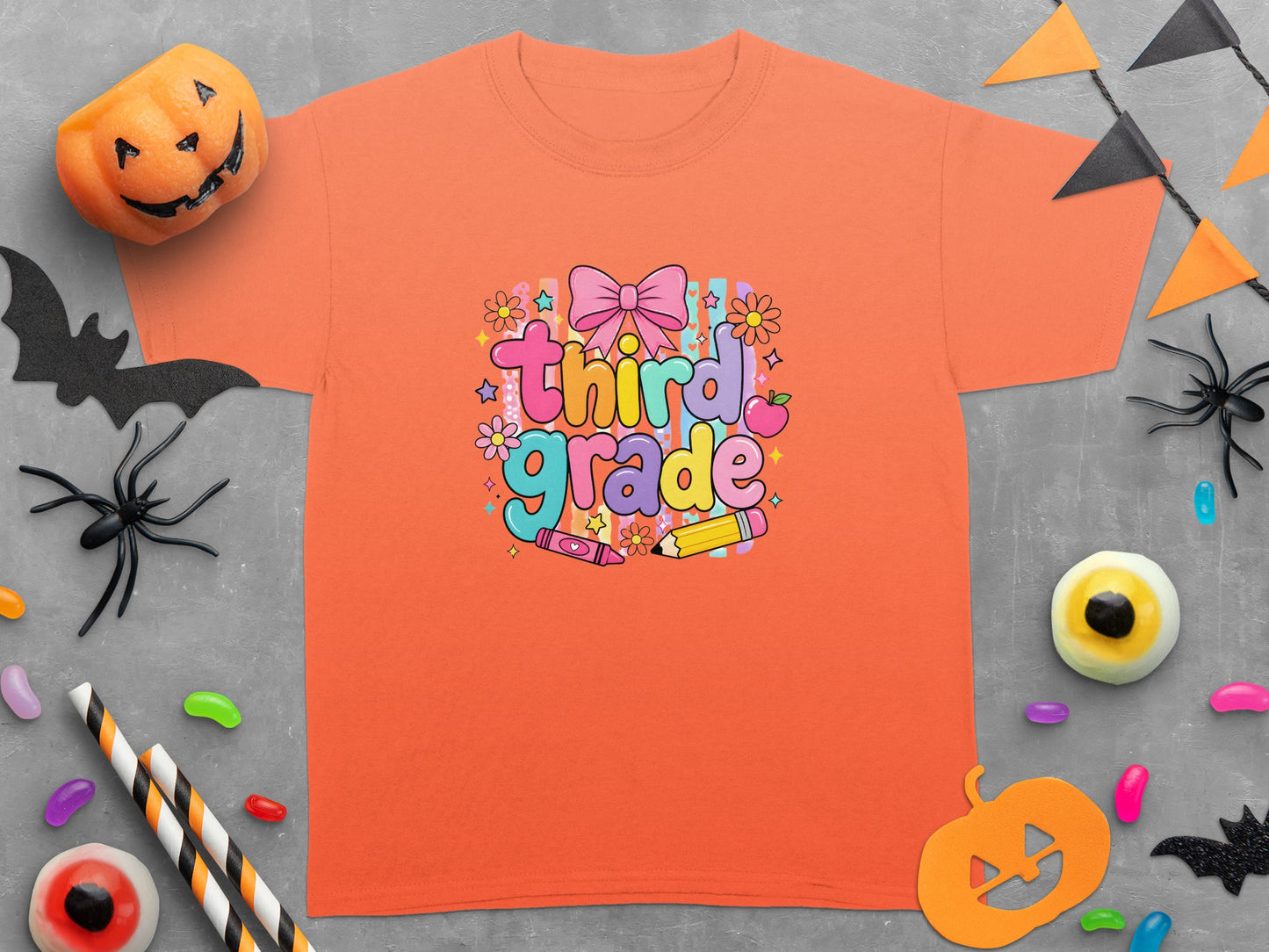 Orange t-shirt with "Third Grade" text, bow, flowers, crayon, and pencil graphic.