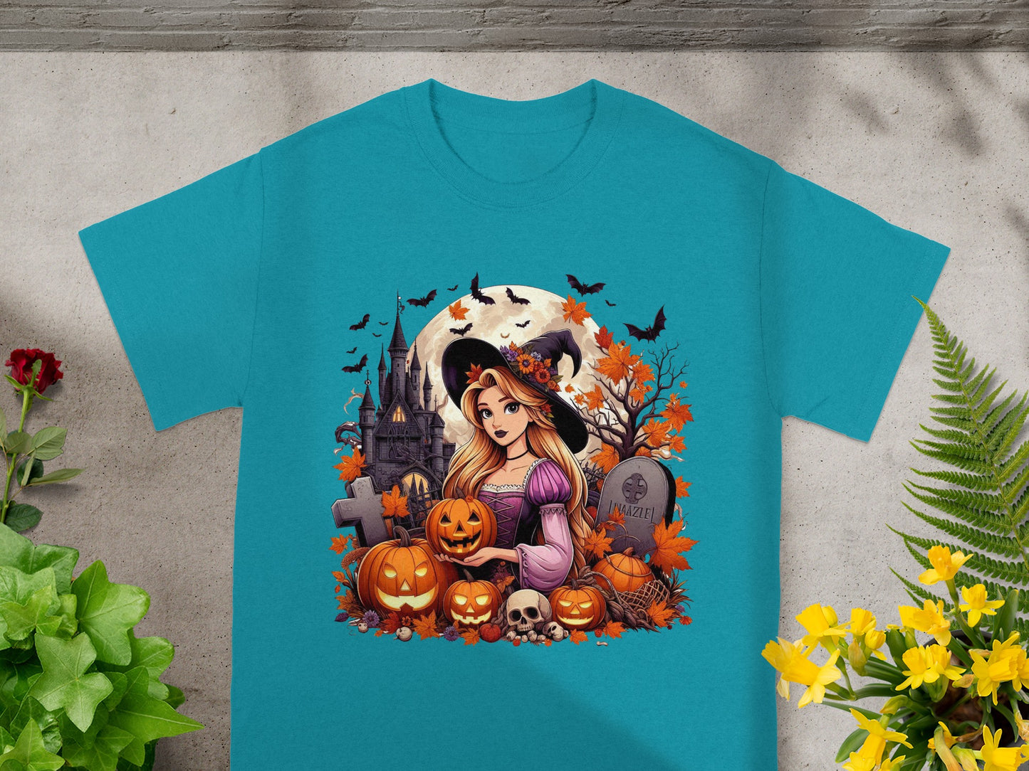 Cartoon witch with pumpkins and haunted castle Halloween graphic on a teal t-shirt.