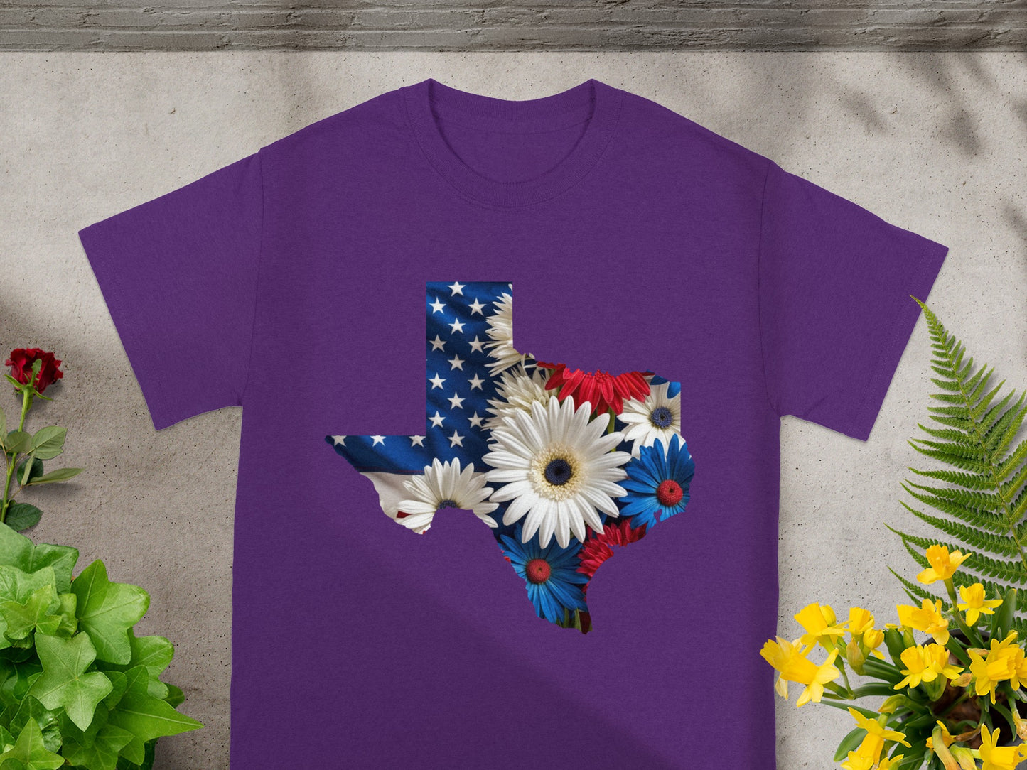 Purple t-shirt with Texas outline filled with American flag and patriotic flowers.