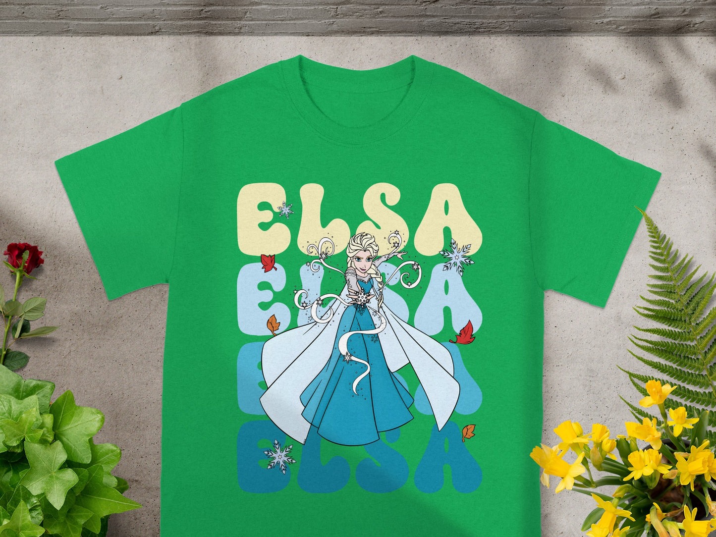Green t-shirt with Elsa from Frozen graphic and text.