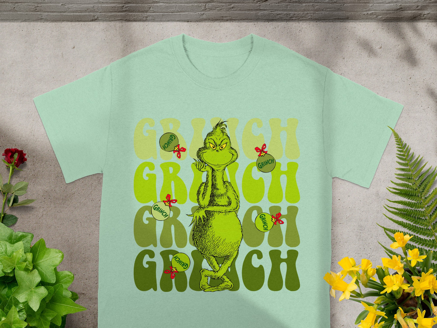 Light green t-shirt with repeating "Grinch" text and cartoon Grinch.