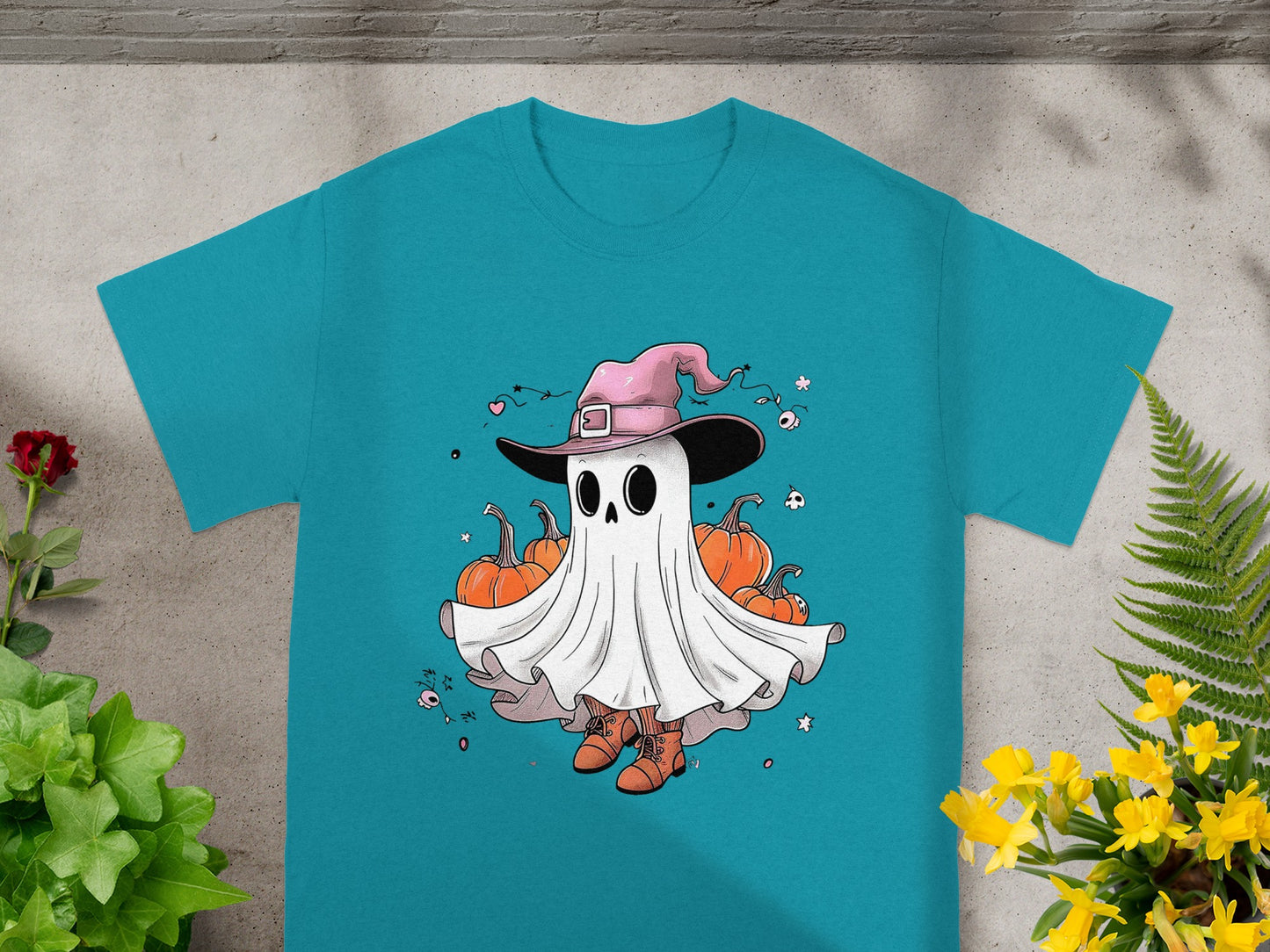 Ghost in a witch hat surrounded by pumpkins and Halloween decorations on a teal shirt.