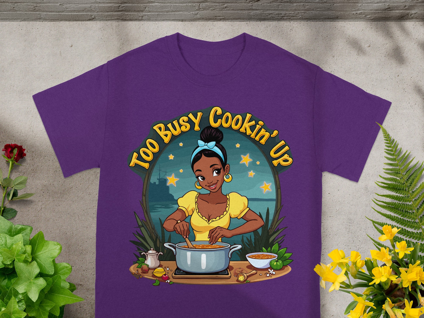 T-shirt graphic with cartoon woman cooking, text reads "Too Busy Cookin' Up".