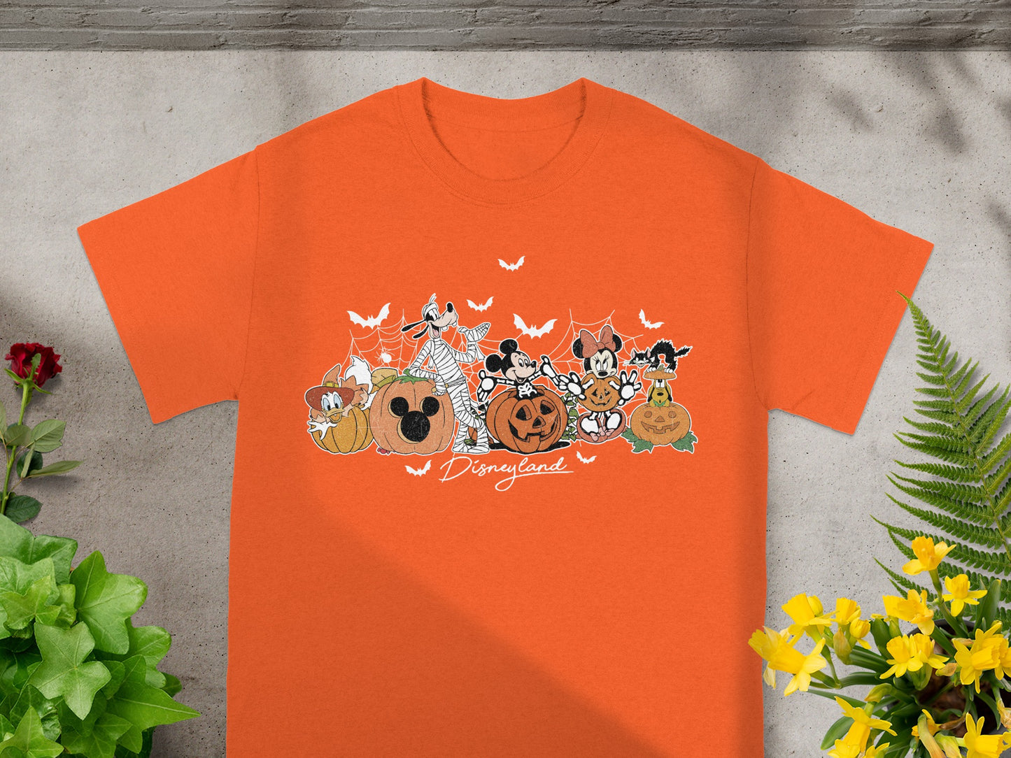Orange t-shirt with Mickey Mouse, Minnie, Goofy, Pluto, Donald, and a black cat with pumpkins and bats.