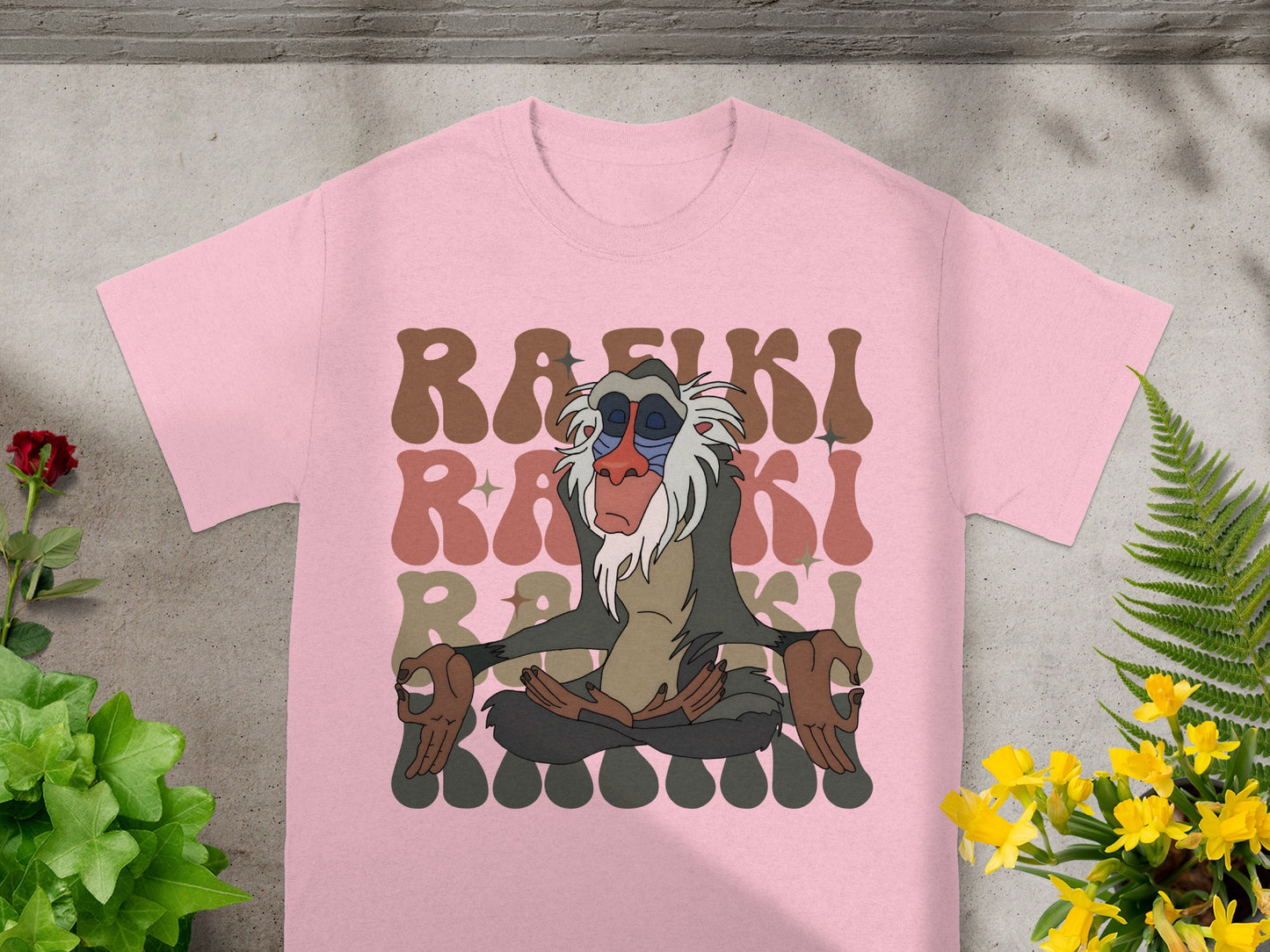 Rafiki meditating on pink t-shirt with brown and beige text.