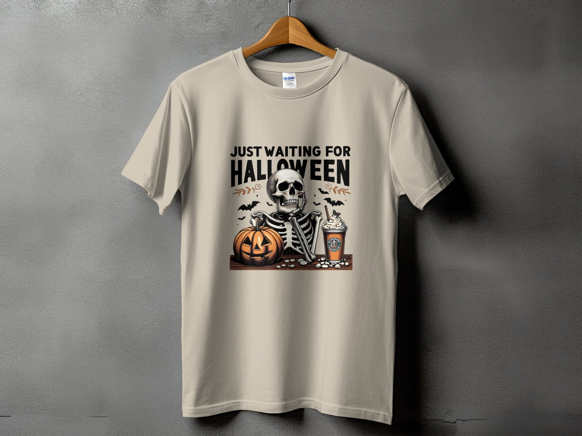 Skeleton with pumpkin and coffee cup on t-shirt, reading "JUST WAITING FOR HALLOWEEN".
