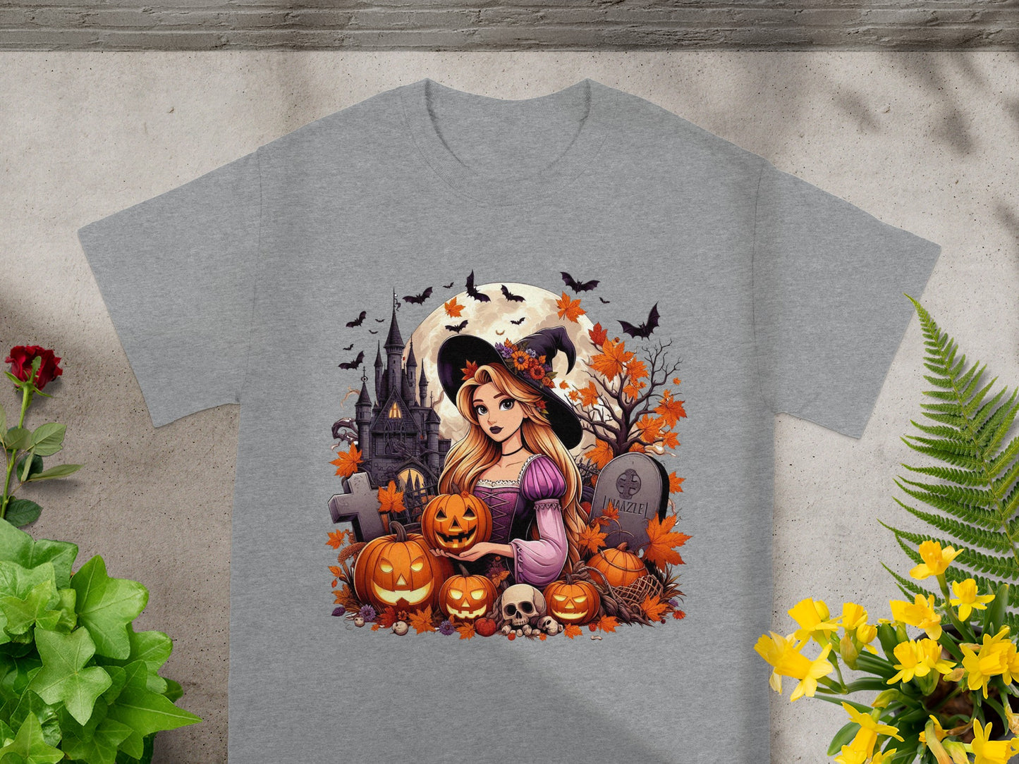 A witch and Halloween elements including pumpkins, skulls, and a castle on a gray t-shirt.