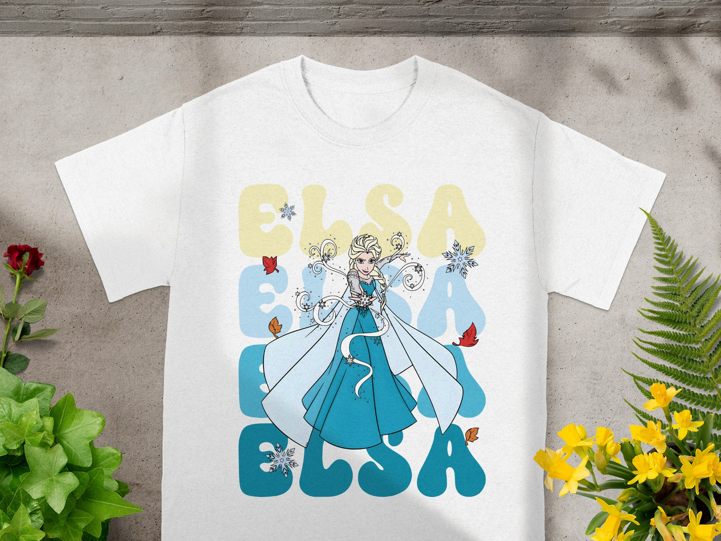 White t-shirt with Elsa and large blue "ELSA" text and snowflakes.