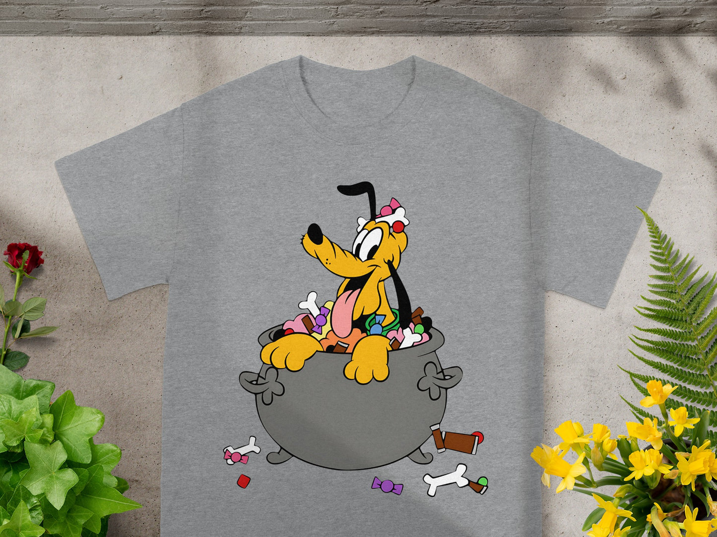 Pluto sits in a cauldron filled with candy, wearing a pink bow and a treat.