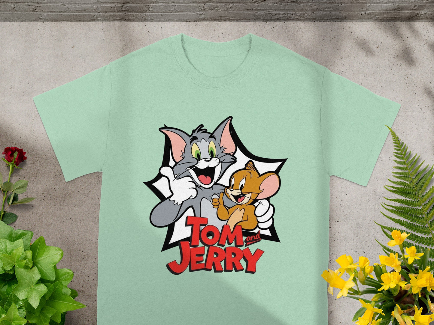 Tom and Jerry characters smiling on a light green t-shirt.