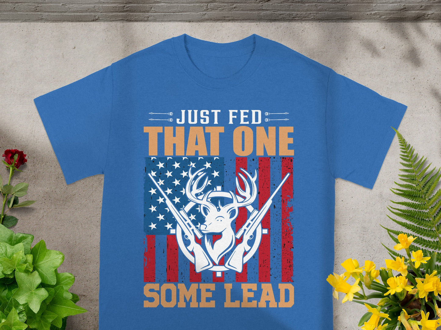 Blue t-shirt with white text "JUST FED" and "SOME LEAD" around a deer head with guns and American flag.