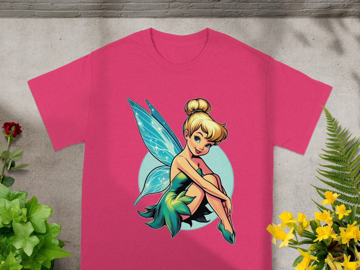 Tinkerbell sitting with light blue background on a pink t-shirt.