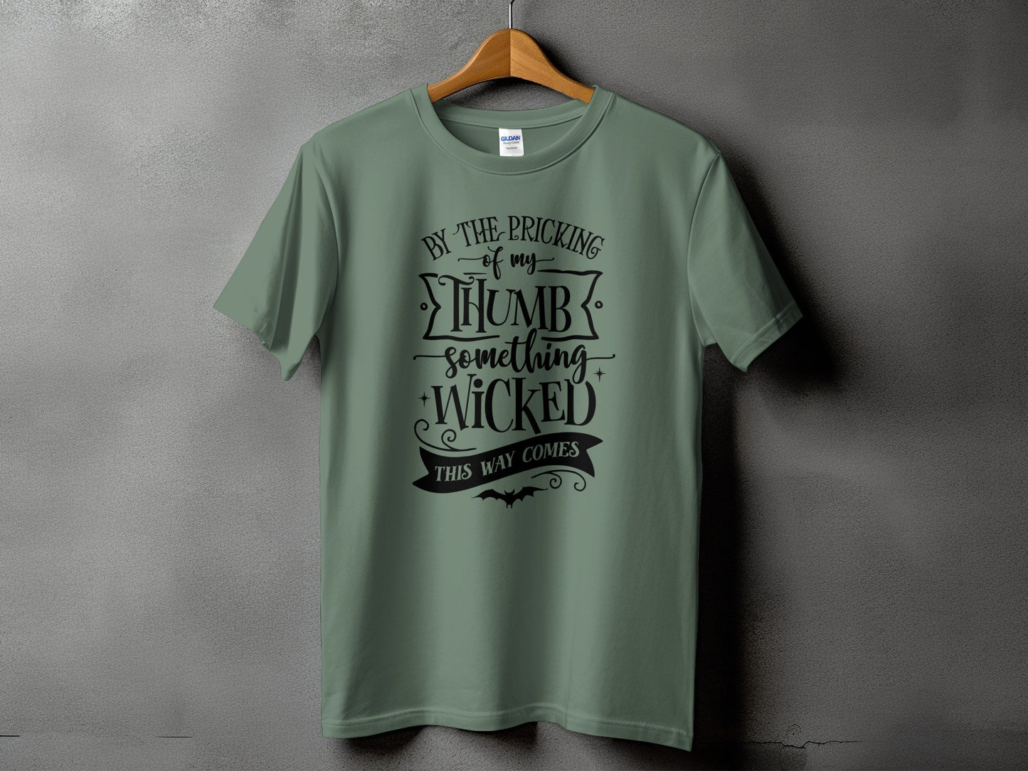 Green t-shirt with black text "By the pricking of my thumb, something wicked this way comes".