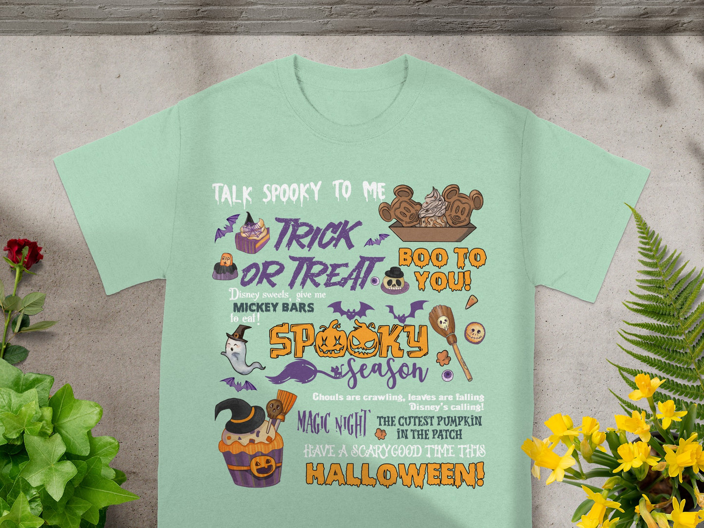 Mint green t-shirt with Halloween theme text and graphics, including Mickey ears.