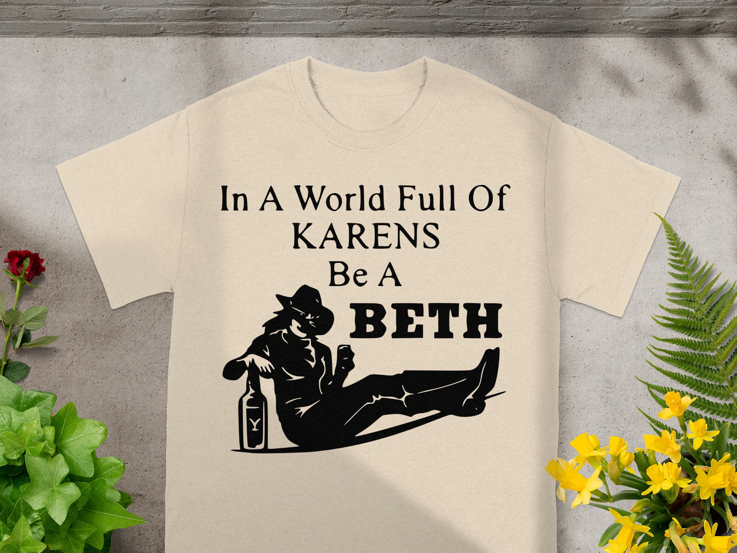 Pale t-shirt with black text and graphic of "In A World Full Of KARENS Be A BETH".