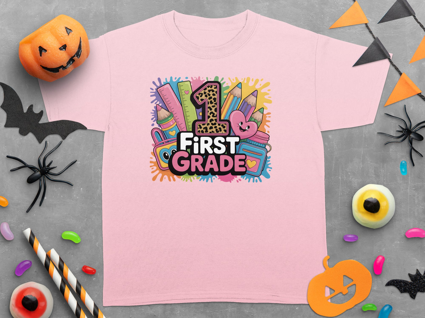 Pink t-shirt with "1st Grade" graphic featuring leopard print 1, pencils, ruler, and heart.