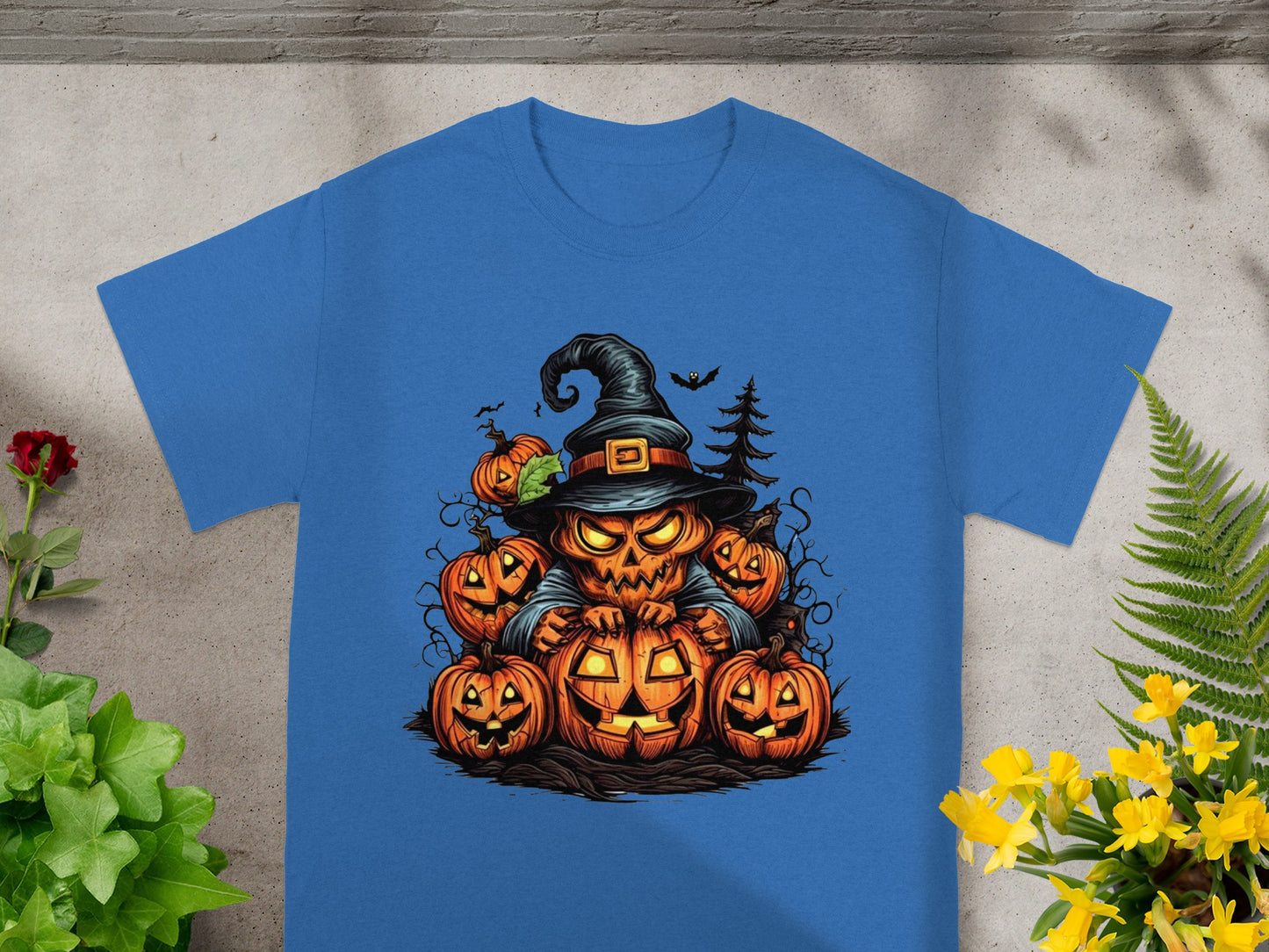 Jack-o'-lantern character wearing a witch hat, surrounded by pumpkins on a blue t-shirt.
