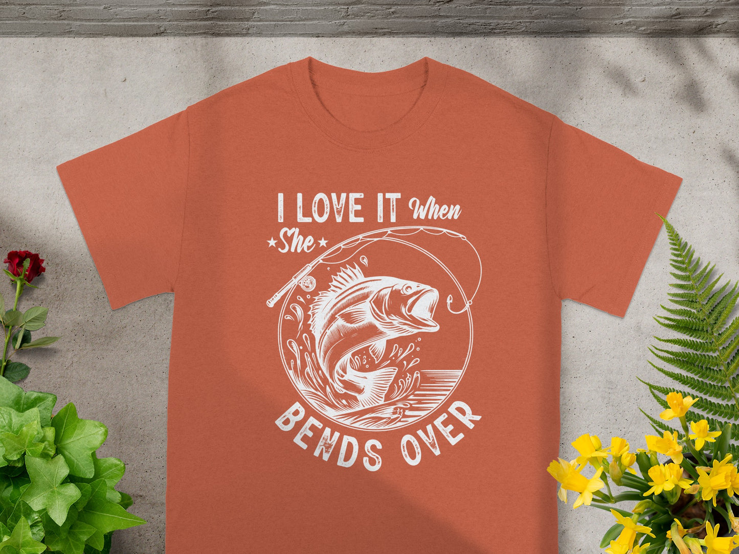 Orange t-shirt with white graphic: "I LOVE IT When She BENDS OVER" and a jumping fish.