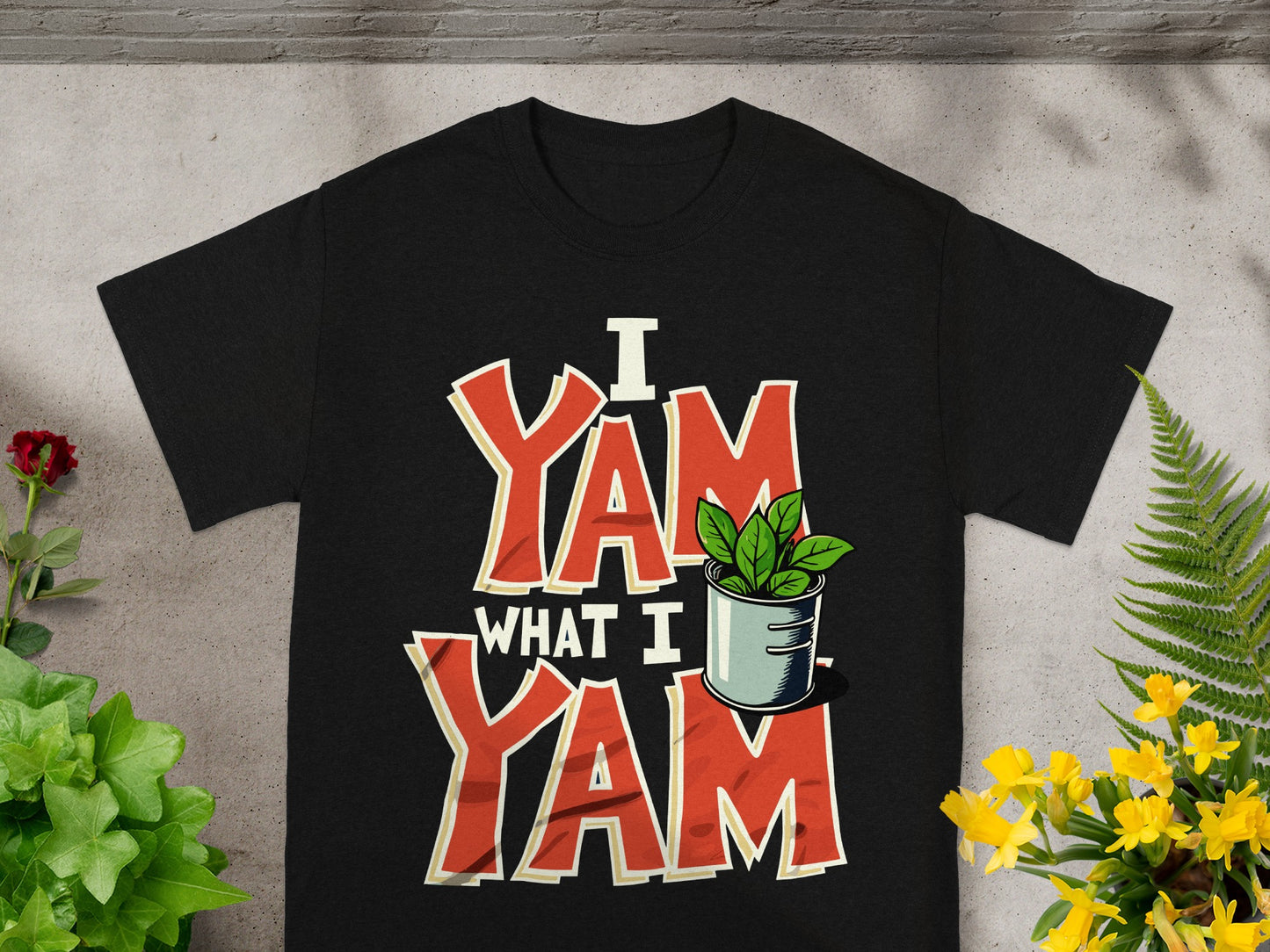 Black t-shirt with "I Yam What I Yam" text and a potted plant.
