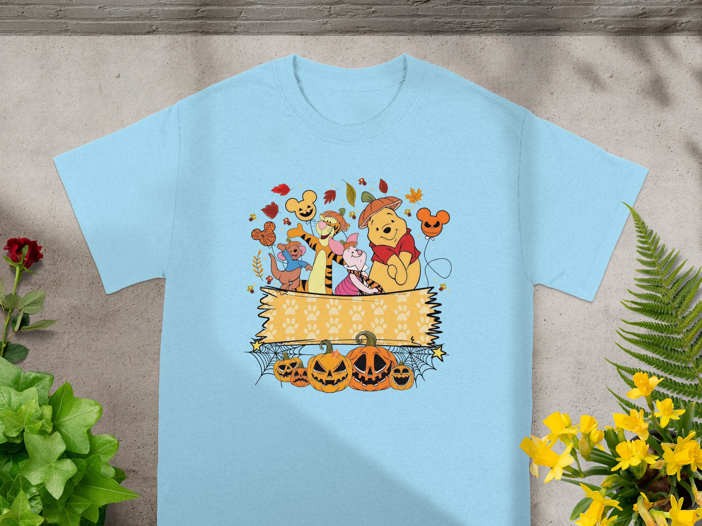 Winnie the Pooh characters with pumpkins and autumn leaves on a light blue t-shirt.