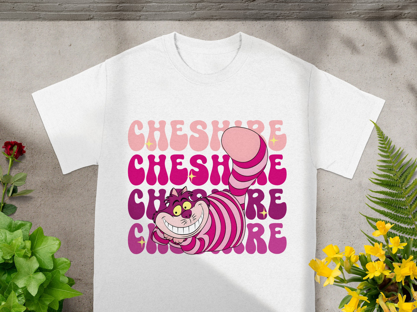 White t-shirt with Cheshire Cat graphic and "Cheshire Cat" text in gradient pink and purple.