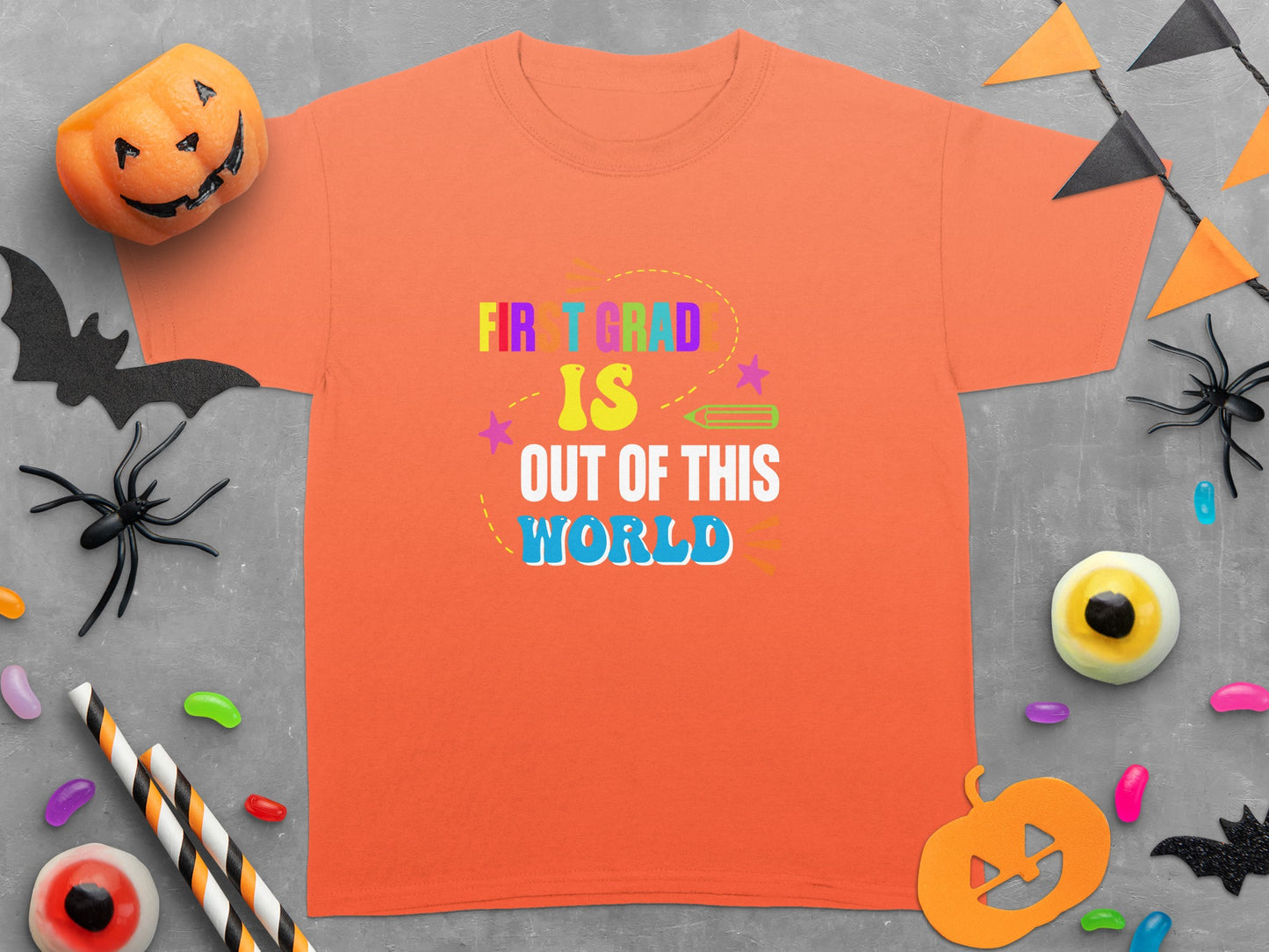 Orange t-shirt with "FIRST GRAD IS OUT OF THIS WORLD" text and Halloween decorations.