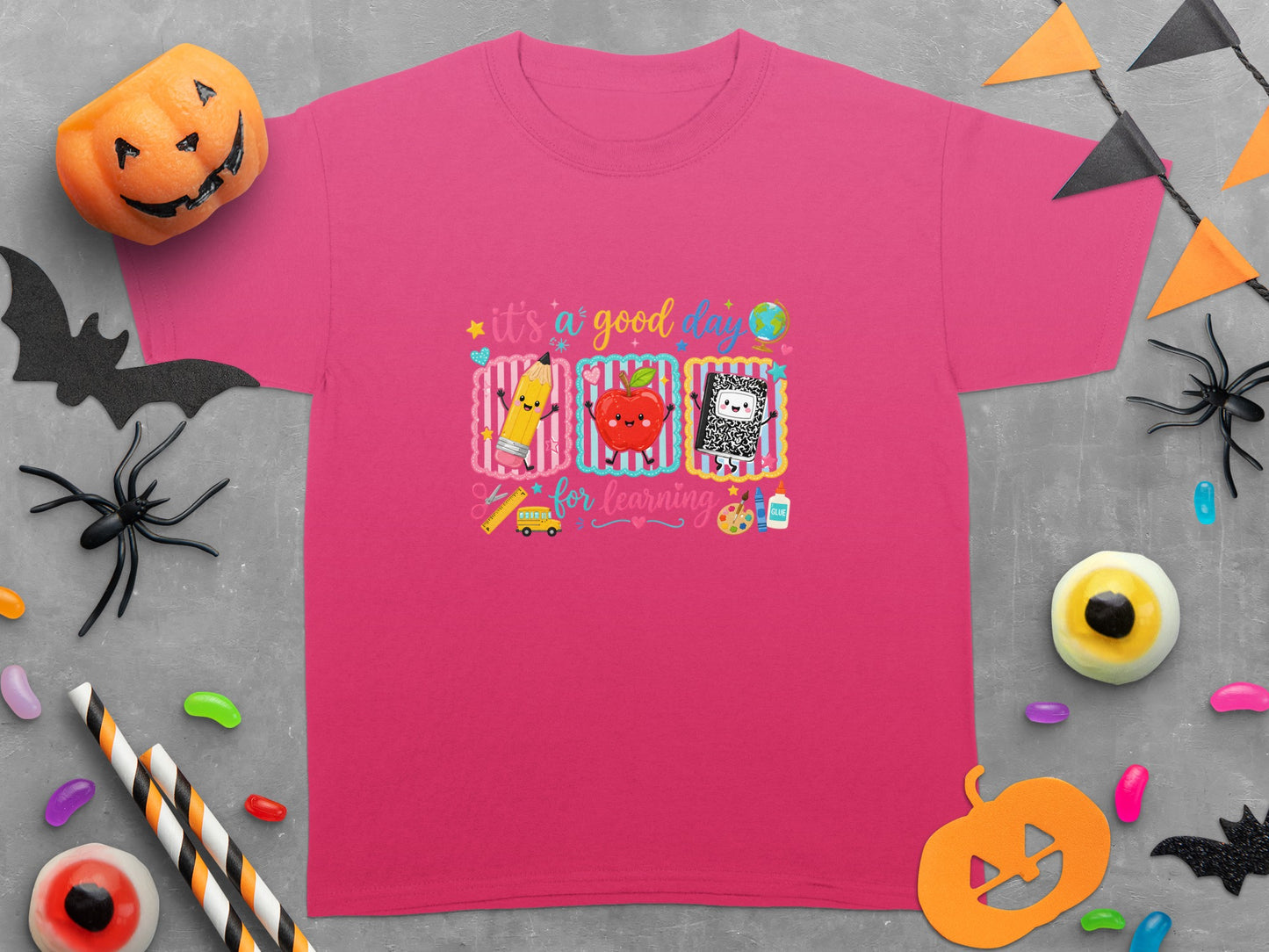 Pink t-shirt with cartoon pencil, apple, notebook, school bus, and text "it's a good day for learning".