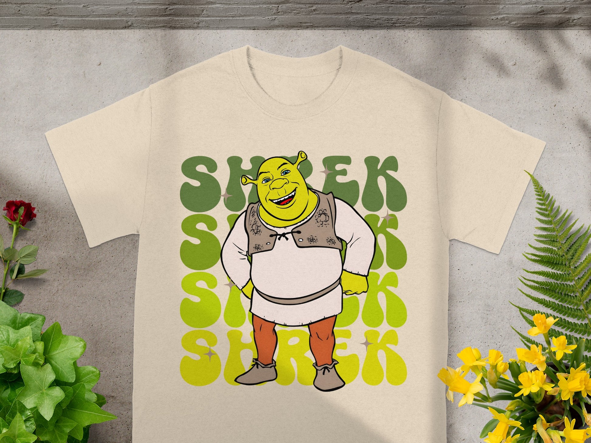 Cream t-shirt with large green Shrek graphic and yellow floral accents.