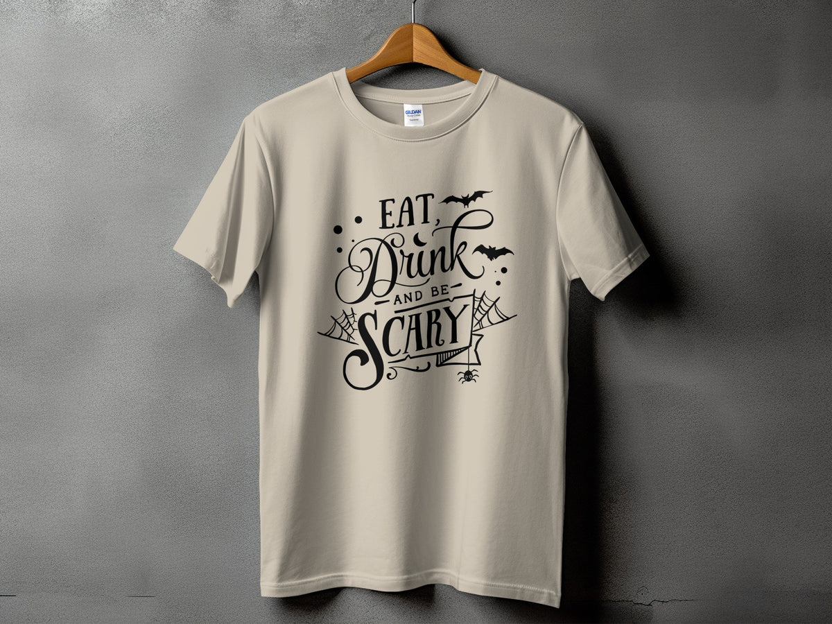 Cream t-shirt with black Halloween text "Eat, Drink and be Scary" and graphics.