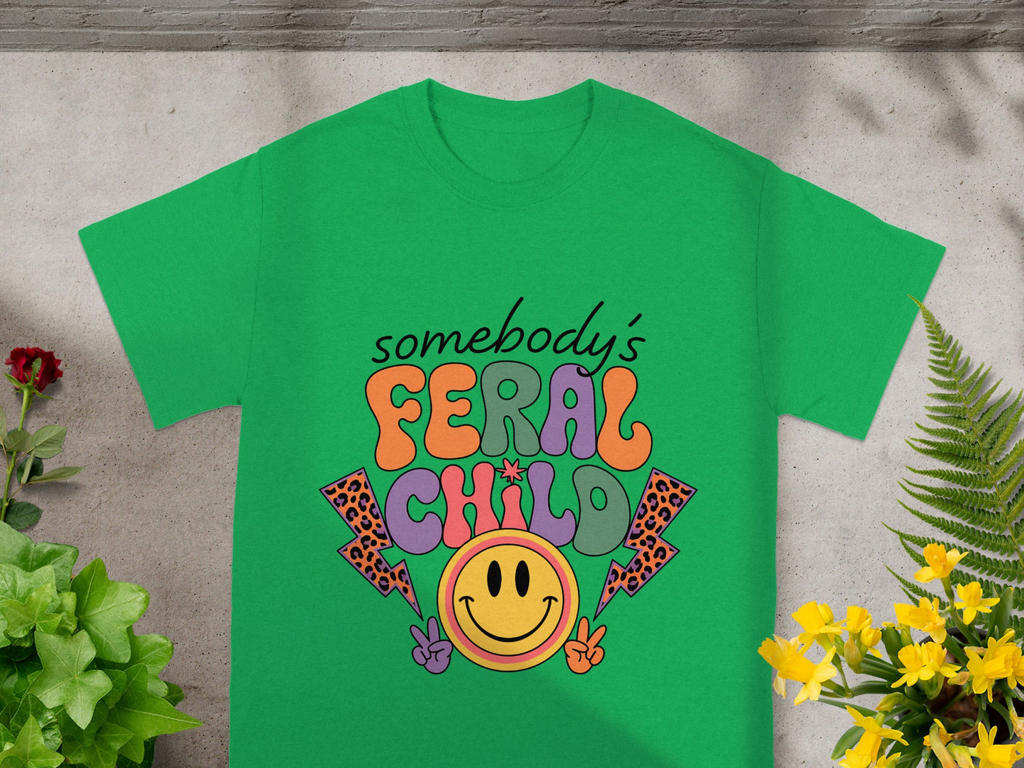 Green t-shirt with text "somebody's FERAL CHILD" and a smiley face.
