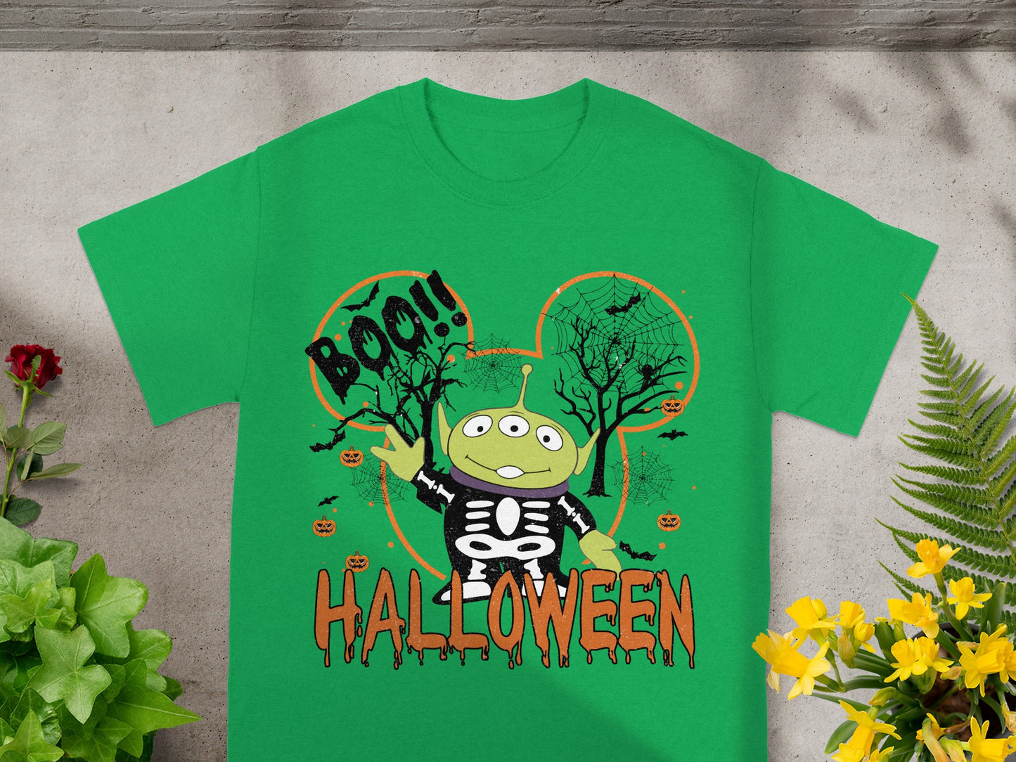 Green t-shirt with Toy Story alien in skeleton costume and Halloween graphic.