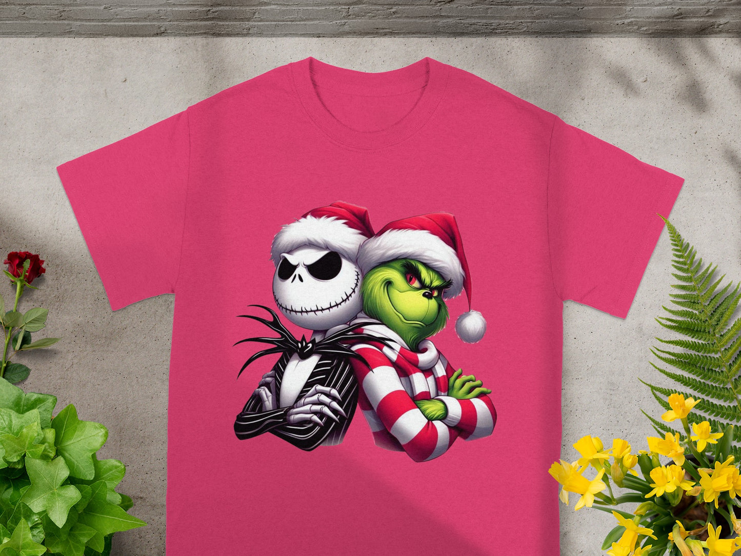 Jack Skellington and the Grinch wearing Santa hats, side-by-side on a pink shirt.