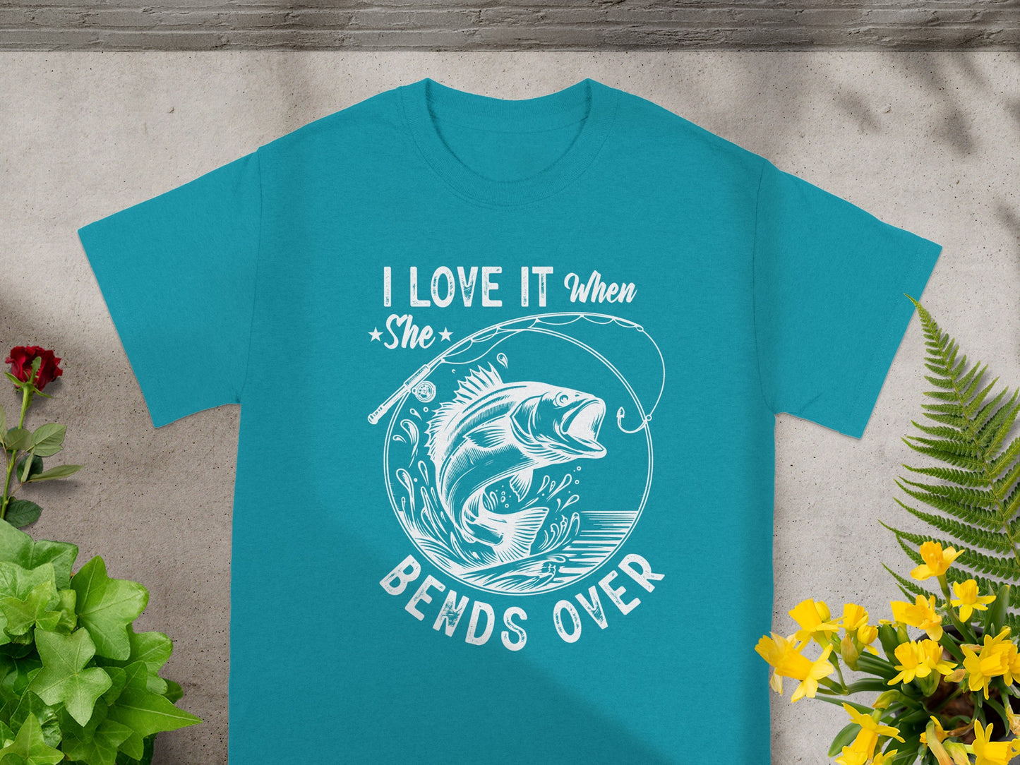 Teal t-shirt with "I LOVE IT When She BENDS OVER" and distressed bass jumping from water graphic.