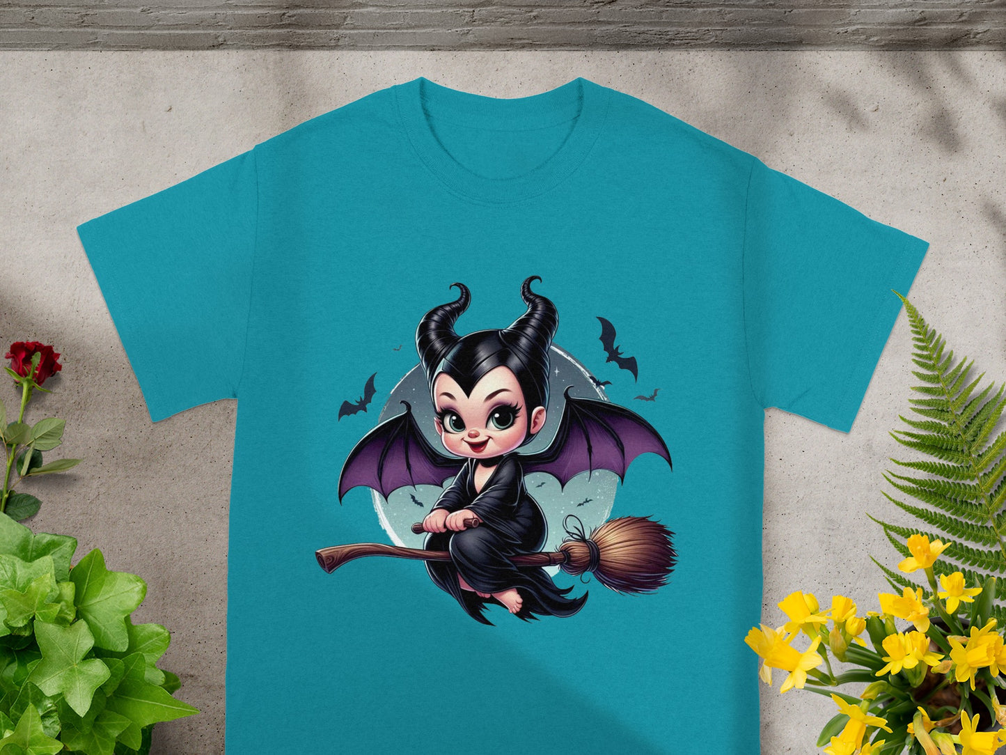 Teal t-shirt with a cartoon Maleficent riding a broomstick with bats.