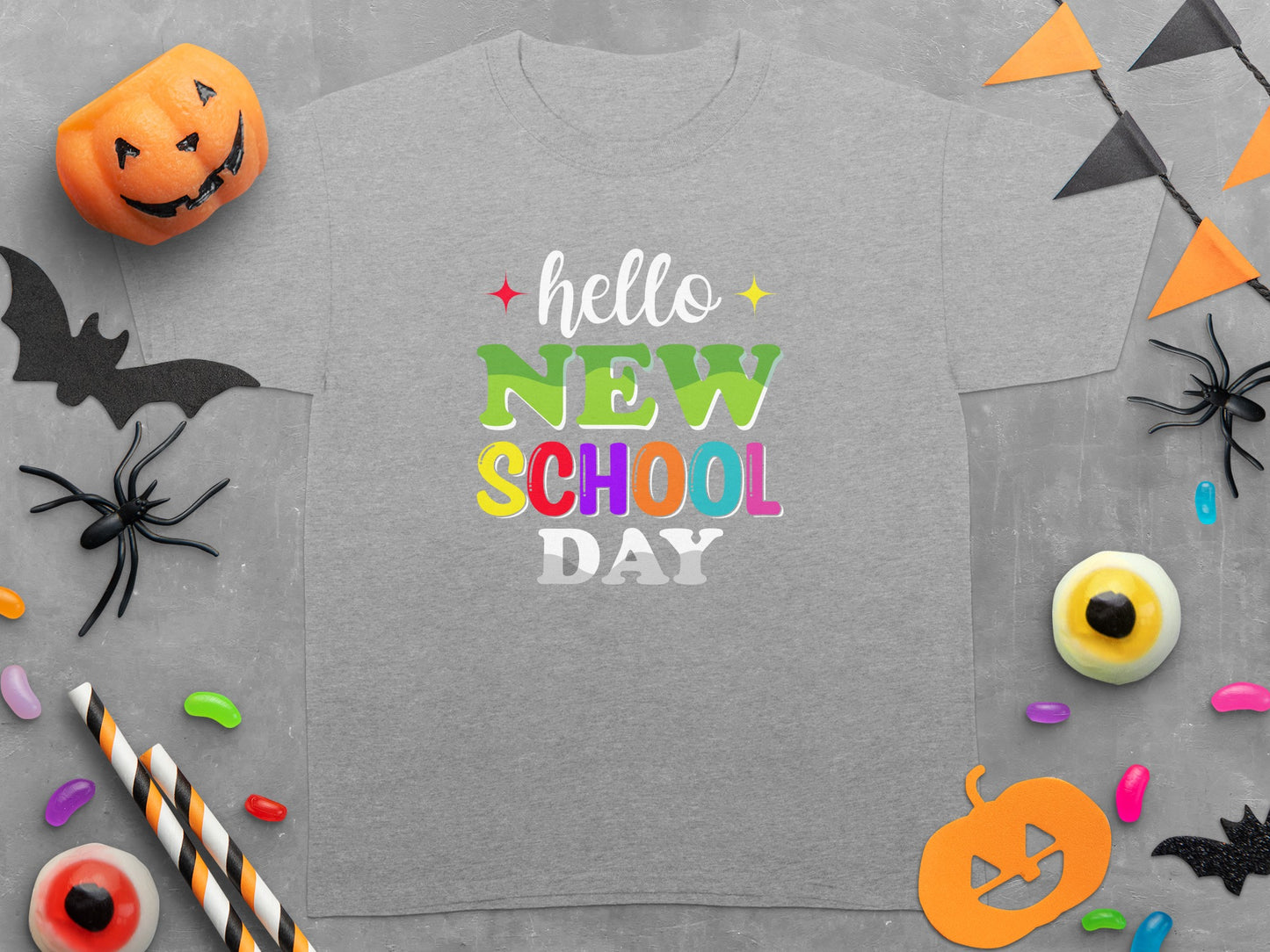 Gray t-shirt with "hello NEW SCHOOL DAY" text in colorful lettering and Halloween decorations.