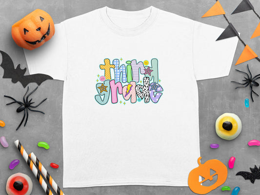 White t-shirt with colorful "Third Grade" text and Halloween decorations.
