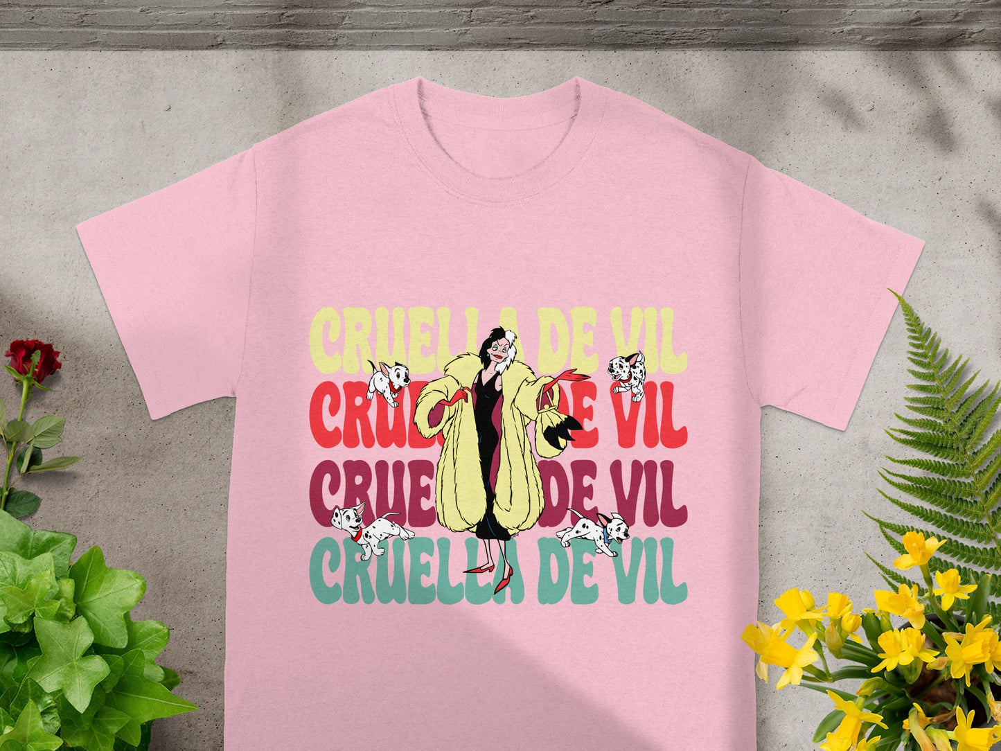 Pink t-shirt with Cruella De Vil graphic and green foliage.