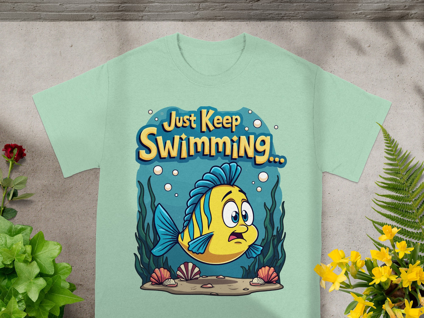 Light green t-shirt with cartoon fish and "Just Keep Swimming" text.